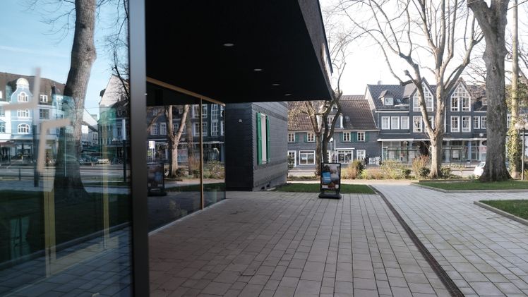 Modernes Gebäude mit dunkler Fassade, Glasreflexion der umliegenden Architektur.