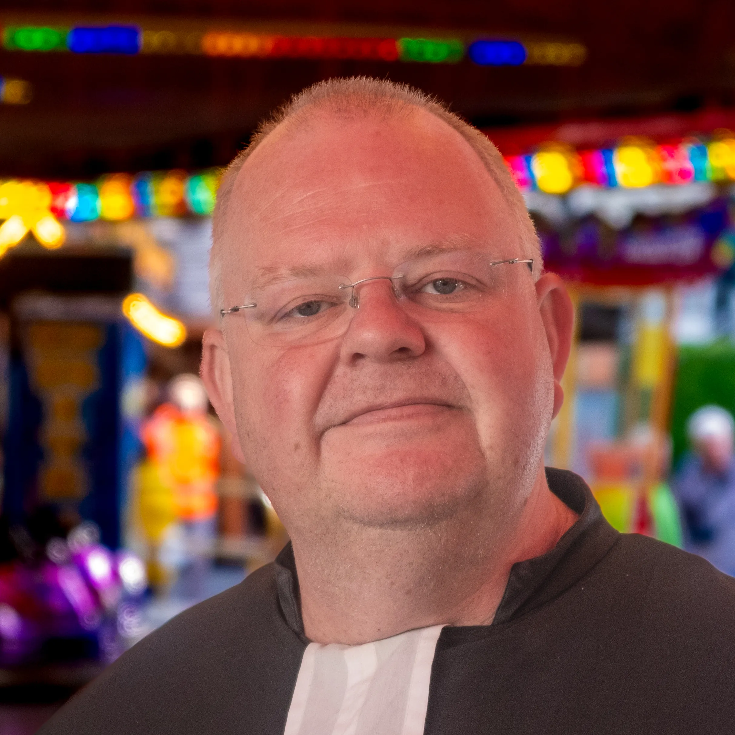 Nahaufnahme-Porträt eines lächelnden Mannes mit Brille und Kragen.