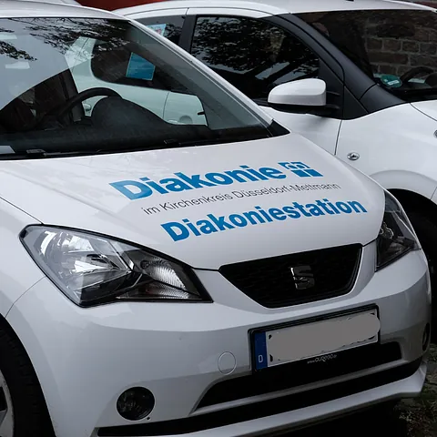 Weißer SEAT Mii PKW mit Aufschrift "Diakonie Diakoniestation im Kirchenkreis Düsseldorf-Mettmann."