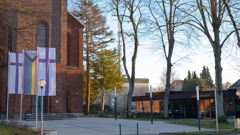 Kirche mit christlichen und Progress Pride Flaggen nahe Gemeindehaus.