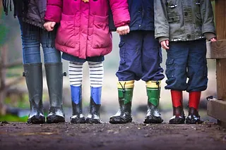 Informationskarte der KiTas Haan mit Kinderbeinen in Gummistiefeln.